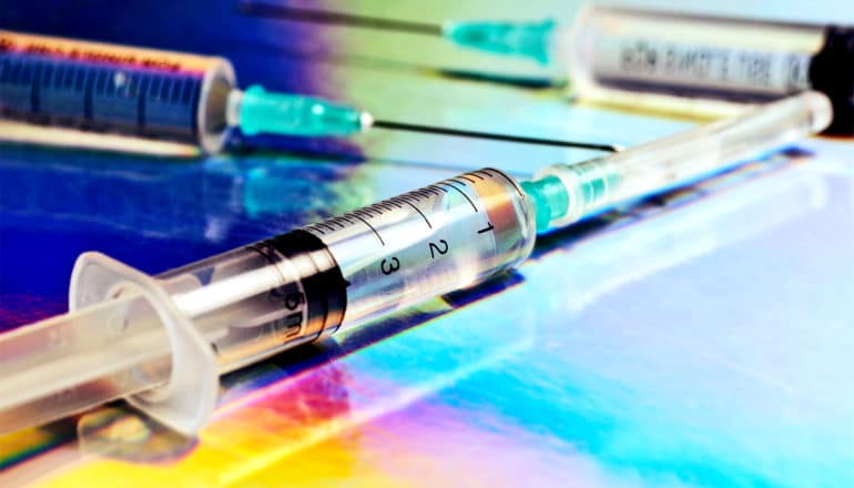 Three syringes on a surface reflecting various colors