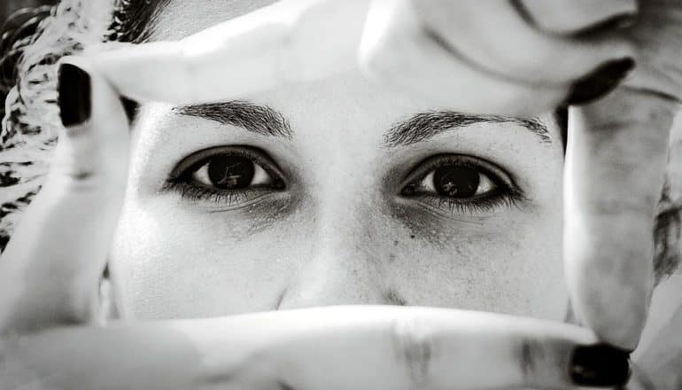 A woman frames her face with her fingers