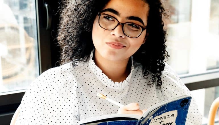 person looks thoughtful holding pencil and notebook