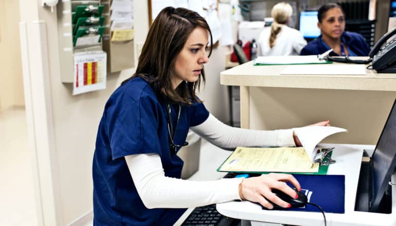 A nurse at a computer station looks at the screen