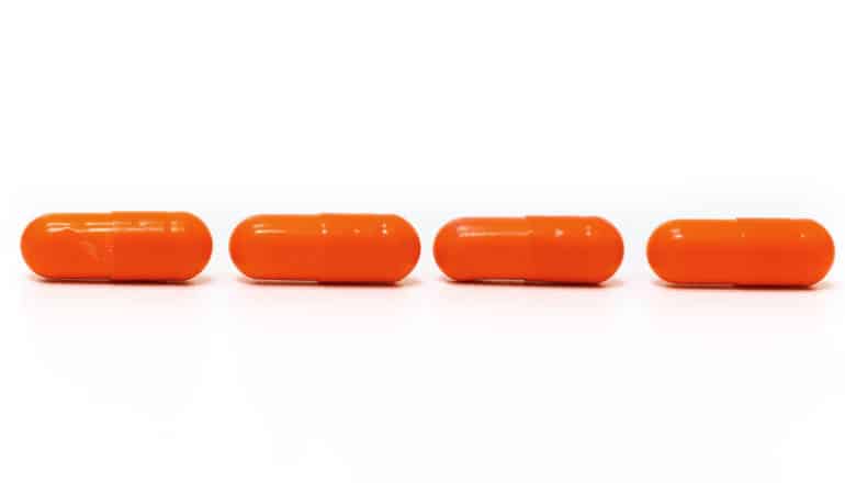 4 orange pills on a white background