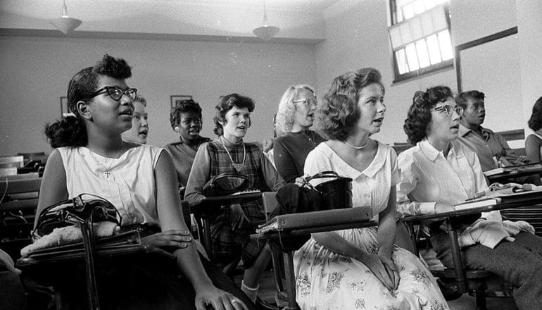 Black and White teens in 1950s styles at classroom desks