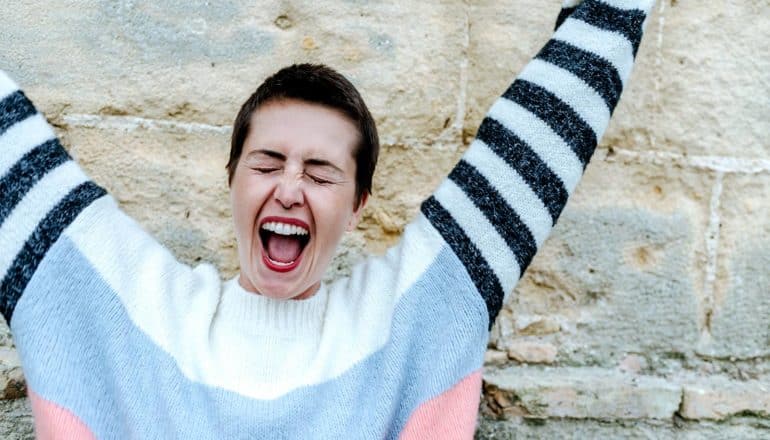 A young woman screams in joy while raising her arms