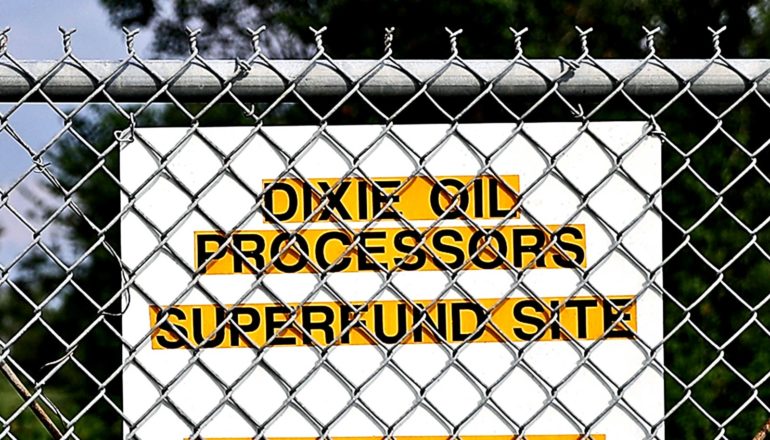 A sign on a fence reads "Dixie Oil Processors Superfund Site"