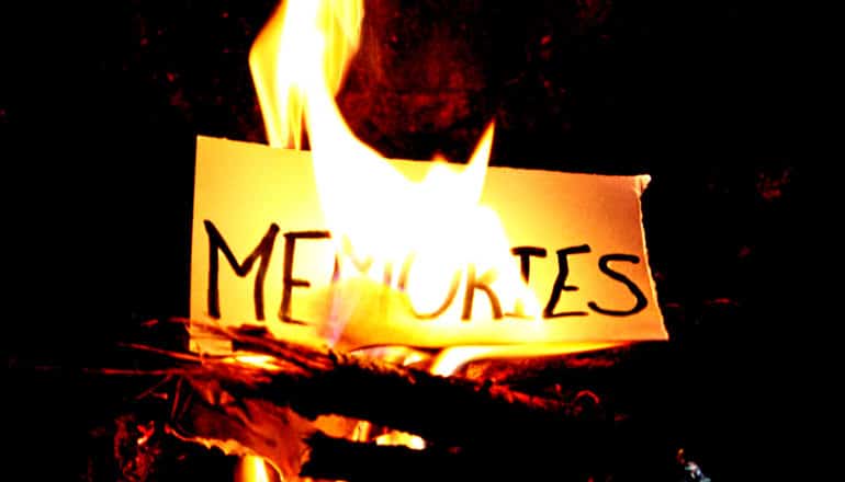 A piece of paper with the word "Memories" on it burns in a fire