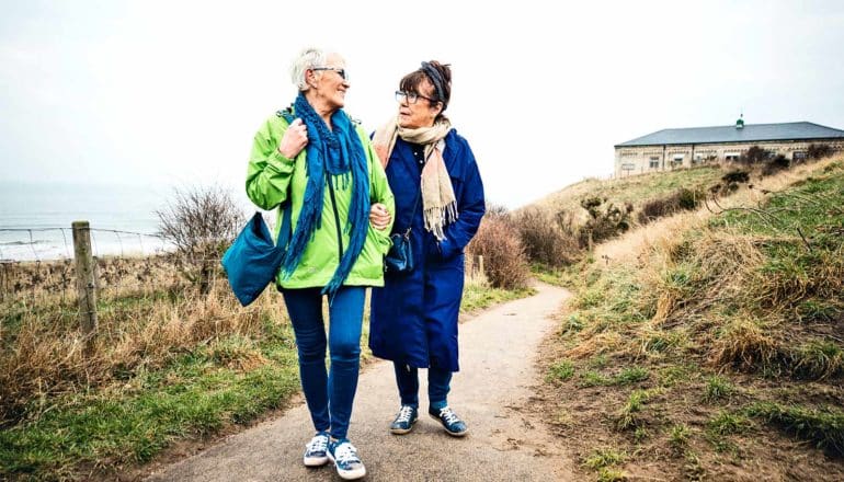 A couple walks together along a cliffside path