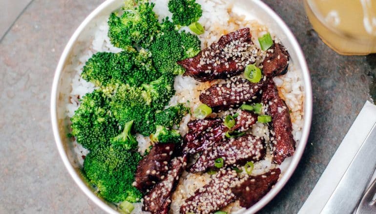 bowl of beef and broccoli with sesame seeds over rice