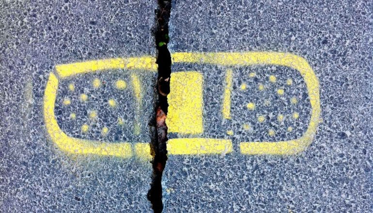 A spray-painted yellow bandaid over a crack in concrete