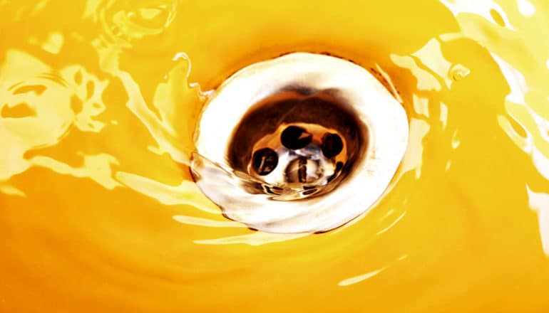 A yellow sink with water flowing into the drain