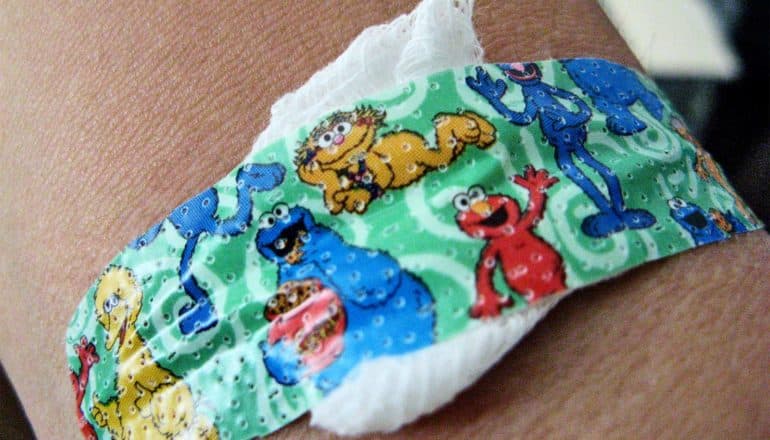 A bandaid over a cotton pad on a child's arm