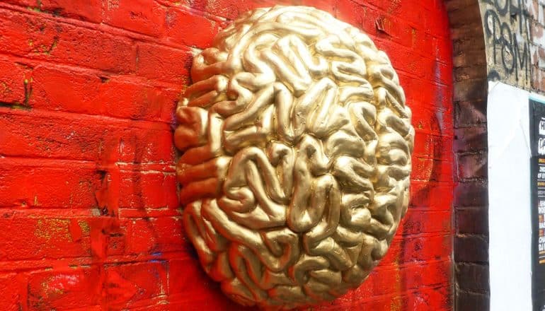 A gold-colored brain mounted on a red brick wall