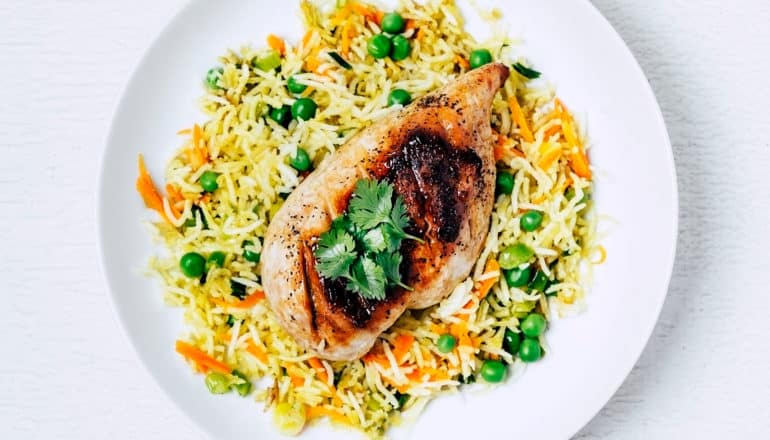 grilled chicken breast with rice and vegetables on white plate