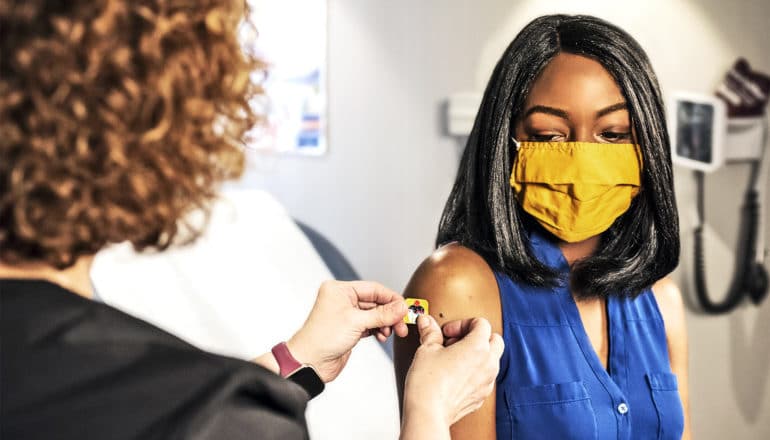 A health worker puts a bandage over a vaccine site on a woman's arm