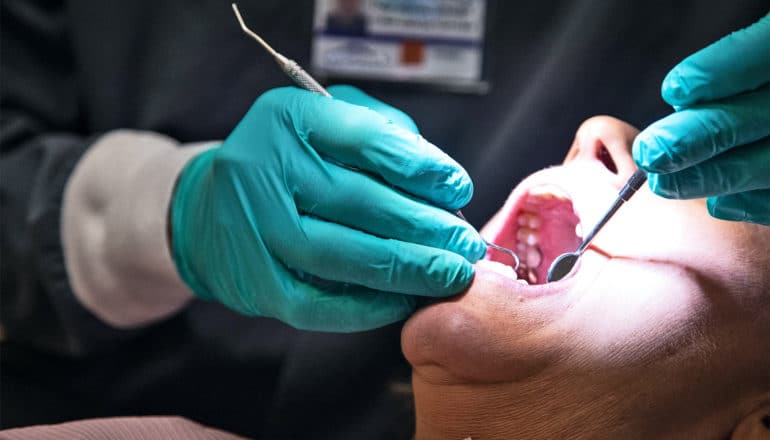 A dentist works on an older woman's gums