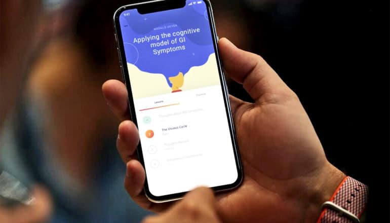 A person holds a phone running the IBS therapy app