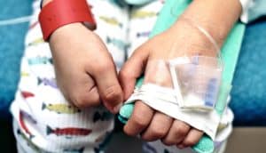 A close-up of a hospitalized child's hands while they get an intravenous drip