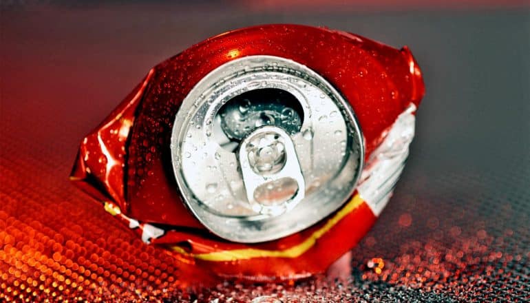 A crushed aluminum soda can on its side facing the camera