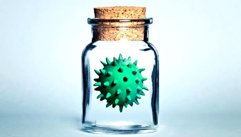 A small glass jar with a cork stopper holds a virus