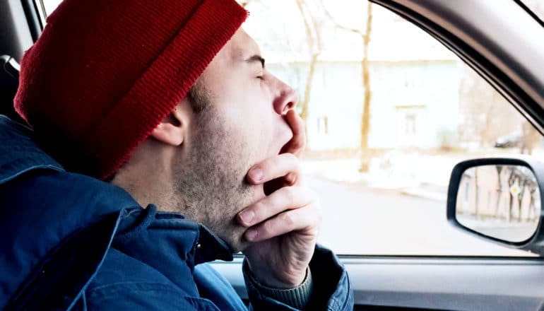 A man driving a car yawns deeply