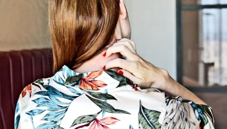 A woman scratches the back of her neck