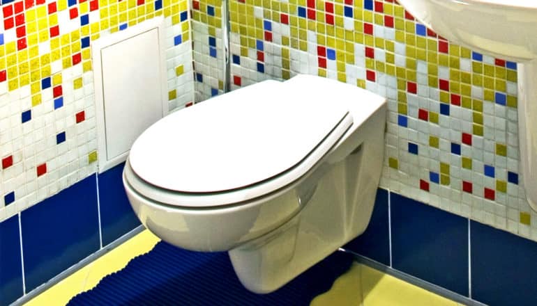 A toilet in a bathroom with red, blue, and yellow tiles