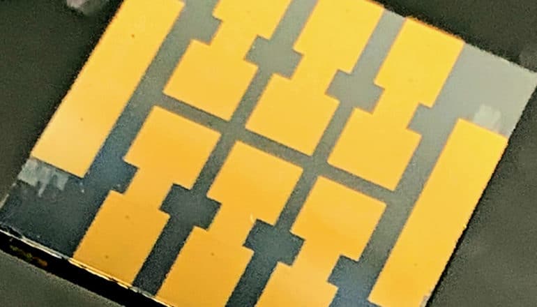 A metal chip has gold-looking pieces laid on top of it