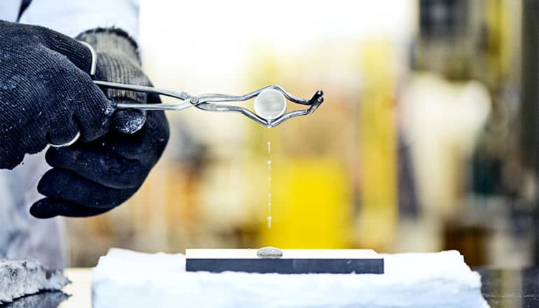 A researcher pours a container of molten, liquid salt onto a surface