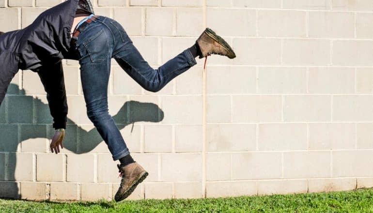 legs and torso of person falling over in front of brick wall