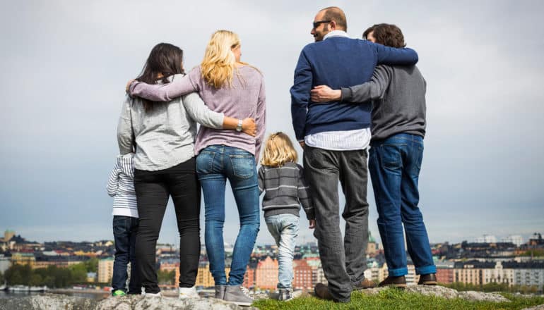 two queer couples and kids stand facing away