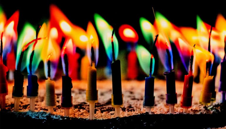 Colorful candles burning on a cake in the dark