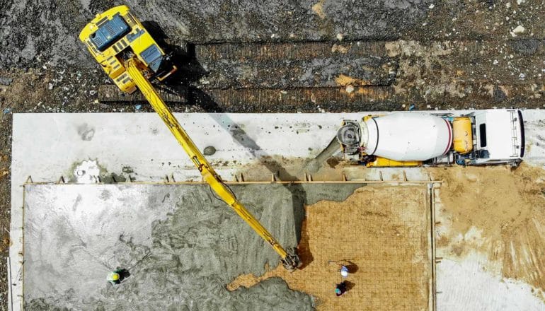 aerial view of cement mixer and excavator pouring foundation