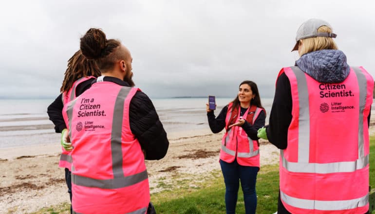 diverse group of people in pink vests that read "I'm a citizen scientist" and "litter intelligence"