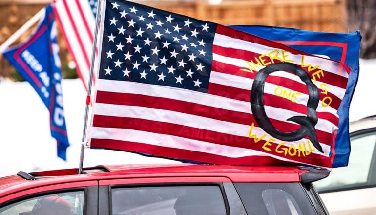 An American flag with a Q on it on top of a car