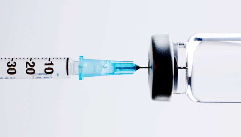 An insulin syringe draws from a glass vial