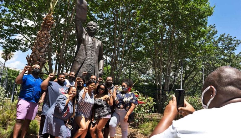 A group poses for a picture in front of a statue of Al Edwards