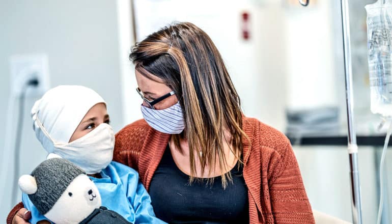 A mother sits with her child on a hospital bed