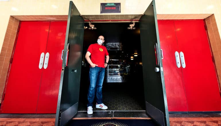 A man stands in the theater doorway with a mask on