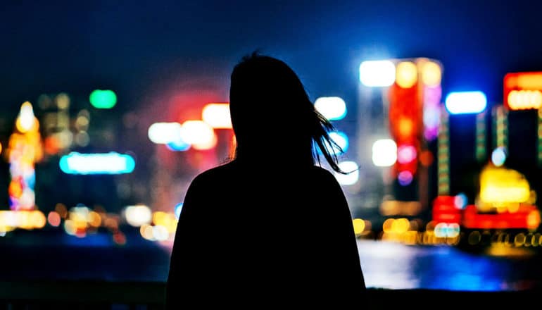 A woman looks at city lights at night