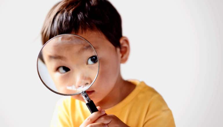 preschooler peers through magnifying glass