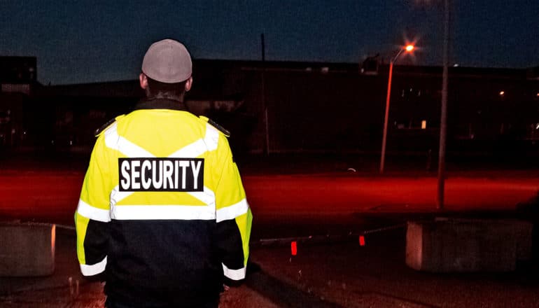 A security guard stands on duty at night near a road