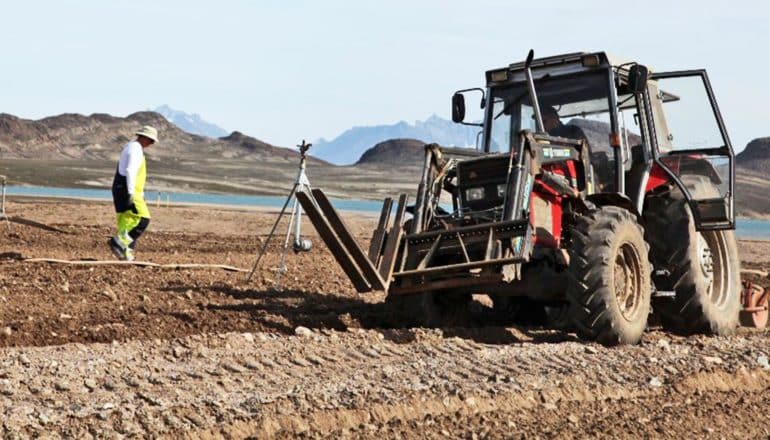 A researcher walks on soil near a tractor