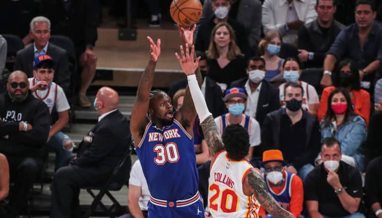 crowd behind two basketball players reaching for ball