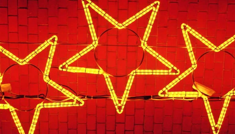 3 star shapes made of yellow lights sit against a red background