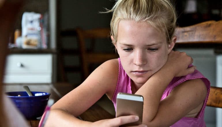 serious teen looks at iPhone