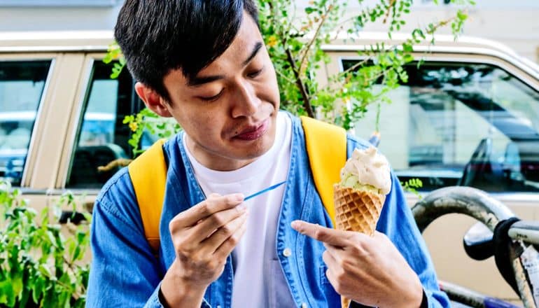 A man looks at this ice cream cone while holding a spoon