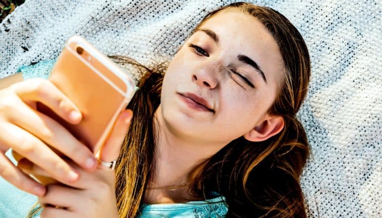 A teen reads her phone with a confused look on her face