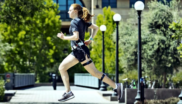 A woman runs wearing the calorie tracker on her waist and leg