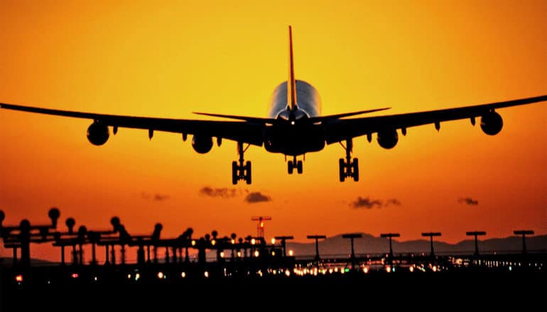 An airplane lands at sunset