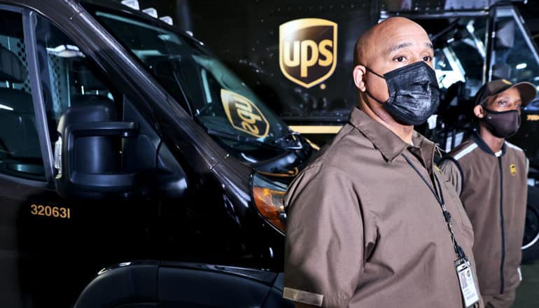 UPS workers wearing face masks in front of delivery vehicles