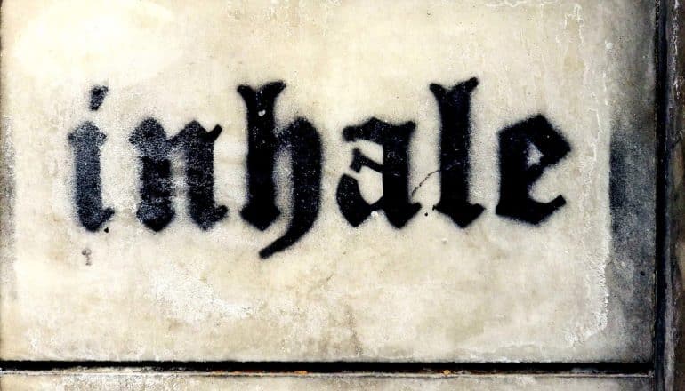 The word "inhale" is painted on a wall